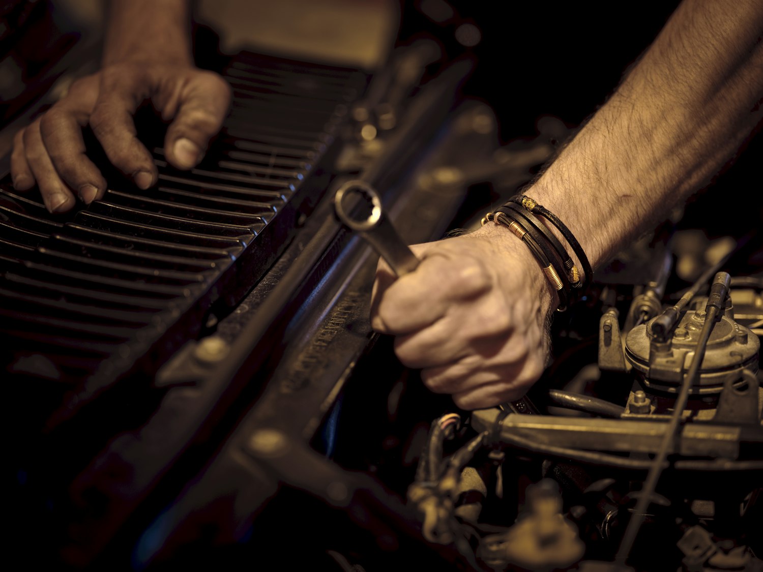 A technician's hands using a wrench on metal finned equipment.